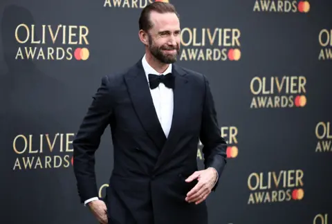Getty Images İngiliz aktör Joseph Fiennes, 14 Nisan 2024'te Londra'nın merkezindeki Royal Albert Hall'daki Olivier Ödülleri'ne katılmak üzere vardığında yeşil halıda poz veriyor