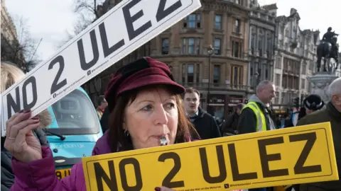 PA Media Woman holding two No 2 Ulez number plates