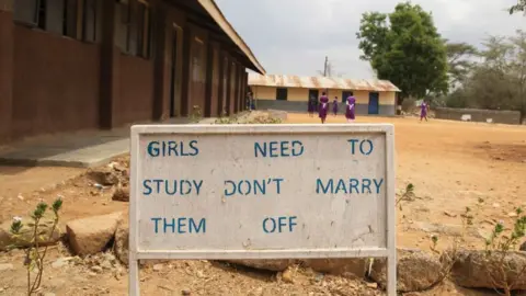 UNICEF A school playground in Africa - a billboard reads "Girls need to study, don't marry them off"