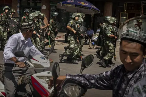 Getty Images Chinese soldiers in riot gear secure the area outside the Id Kah Mosque, after Imam Jumwe Tahir was killed by assailants following early morning prayers on July 30, 2014 in old Kashgar, Xinjiang Uyghur Autonomous Region, China.