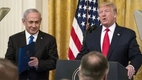 Getty Images Israeli Prime Minister Benjamin Netanyahu smiles as US President Donald Trump unveils his Middle East peace plan at the White House (28 January 2020)