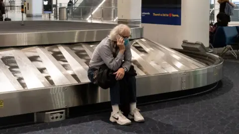 Getty Images A traveler sits in baggage claim at LaGuardia Airport in New York, on December 24, 2021