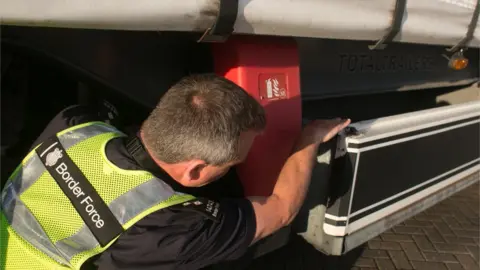 Getty Images Border Force staff check underneath a lorry