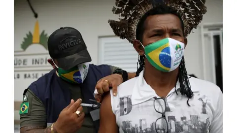 REUTERS/Bruno Kelly Health agent of the Special Indigenous Sanitary District of Manaus administers a coronavirus vaccine against a native of the Makira village, of the Mura ethnicity on the banks of the Urubu river in Itacoatiara, Amazonas, February 13, 2021