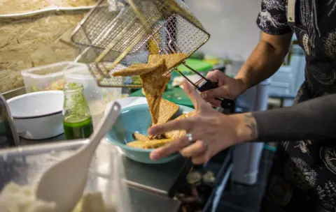 BBC Iiuri pouring tempeh from the deep fryer into a bowl