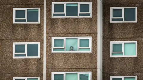 Getty Images A woman in one of the locked-down public housing towers in Melbourne's west stares out the window