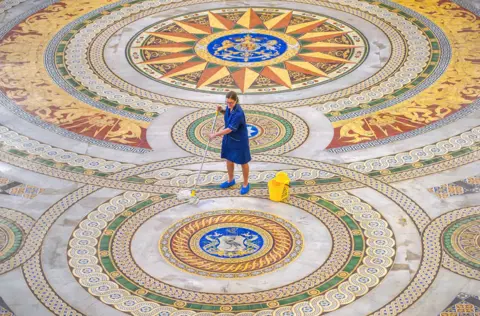 Peter Byrne/PA Media Louise Brewis cleans the Minton floor at St George's Hall, Liverpool, before it goes on display to the public.