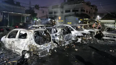 Reuters Police officers inspect the damage after cars were set on fire at Brimon (Mobile Police) Dormitory Complex