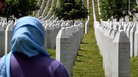 AFP A woman stands near tombstones at a cemetery to honour the victims of the 1995 Srebrenica massacre