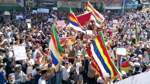 EPA Members of a large crowd wave Druze flags at anti-government protest in Suweida on 8 September 23