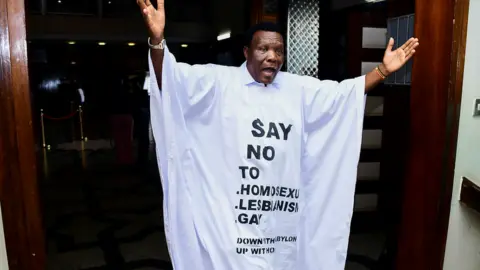 Reuters Ugandan MP John Musira dressed in an anti-gay gown gesturing as he leaves the chambers during the debate of the Anti-Homosexuality bill