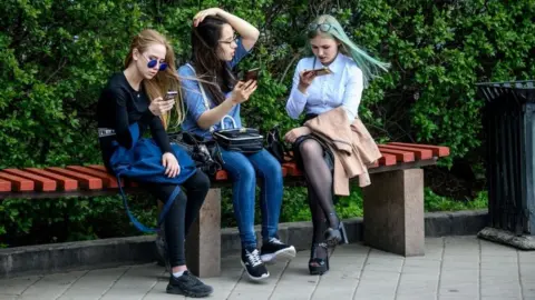 Getty Images Young people looking at their phones