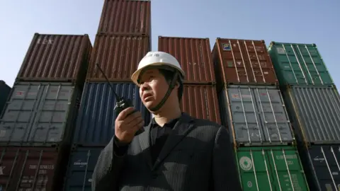 AFP A worker monitors the loading of shipping containers in Hubei province in China