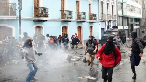 Getty Images Demonstrators clash with riot police during protests over President Moreno's move to end four-decade-old fuel subsidies