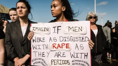 Getty Images Protesters hold signs as they take part in a march against gender based violence and in solidarity with women who have been subject to violence and in memory of those who have been killed, at the North Beach in Durban, on September 7, 2019