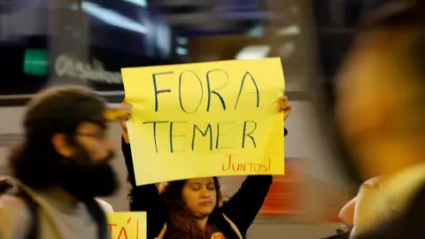 Reuters People hold a banner as they protest against Brazil's President Michel Temer in Sao Paulo, Brazil