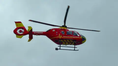 The Midlands Air Ambulance's red and yellow helicopter is pictured in the grey skies