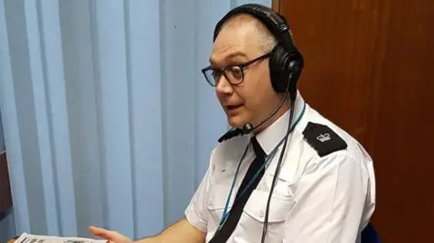 Leicestershire Police A seated police officer wearing a headset