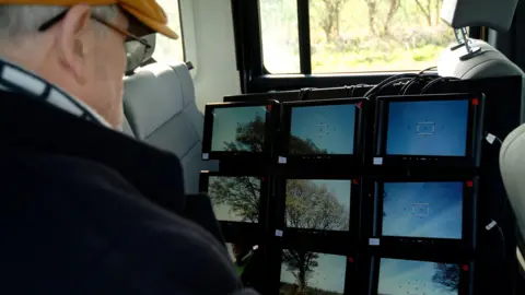 David Hockney looking at images on multiple screens