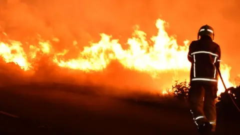 West Yorkshire Fire and Rescue Service A firefighter tackles a fire in Pontefract in August 2022