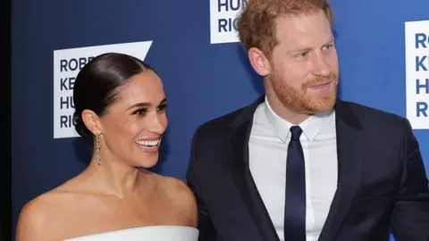 Mike Coppola Prince Harry and Meghan pose for a photo.