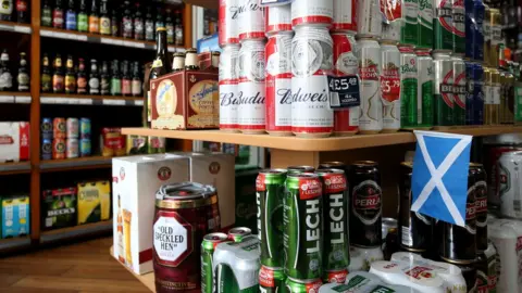 PA Media Cans of beer stacked up in an off licence