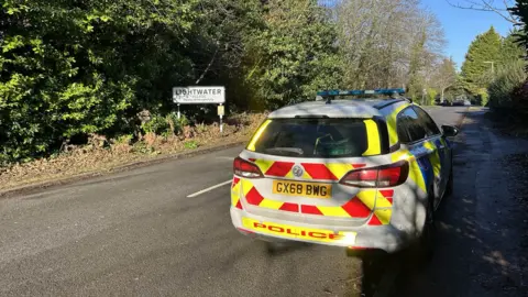 A police car by a sign for Lightwater