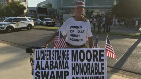 Peter Grove displays his pro-Moore campaign signs at the Donald Trump rally in Huntsville