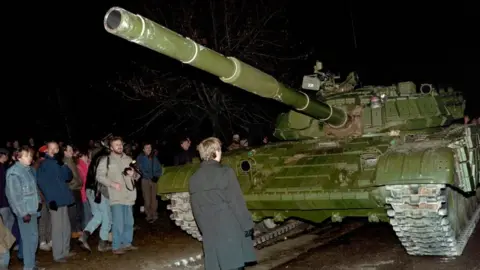 Getty Images A Lithuanian demonstrator stands in front of a Soviet Red Army tank during the assault on the Lithuanian Radio and Television station on January 13, 1991 in Vilnius