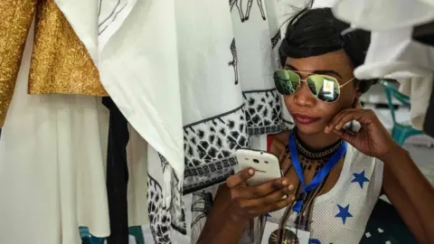 AFP An event organiser looking at a phone at Swahili Fashion Week in Dar es Salaam, Tanzania - Saturday 2 December 2017