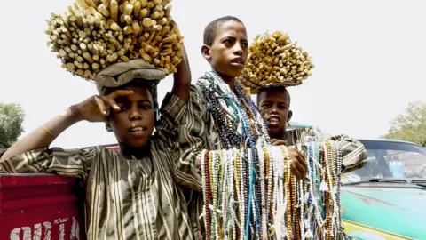 Getty Images Three boys hawking wares in Nigeria