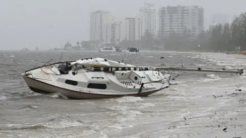 EPA Sebuah perahu kecil yang dicuci di pantai berawan.