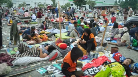 AFP/Getty Images People sit outside a hospital in Palu. Photo: 29 September 2018