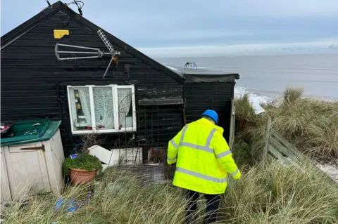 Jon Ironmonger/BBC A council building control surveyor is assessing the weather conditions and if three properties are ready to be demolished