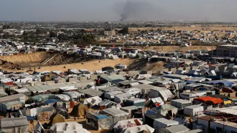 Reuters Smoke rises from the Khan Younis, as seen from makeshift camp for displaced Palestinians in Rafah, in the southern Gaza Strip (22 January 2024)