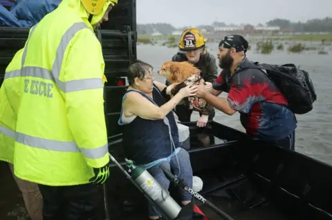 Getty Images A woman and her dog being rescued