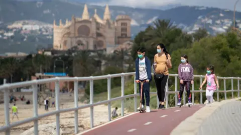 Getty Images Children in face masks by a beach in Mallorca