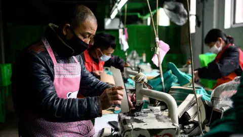 AFP Workers wearing face masks as they make insoles at a factory