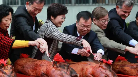 Getty Images Carrie Lam (third from left) and other officials cut into roast suckling pigs at the opening ceremony of the Hong Kong West Drainage Tunnel Project - Tunnel Breakthrough Ceremony. 17FEB11 (Photo by Jonathan Wong/South China Morning Post via Getty Images)