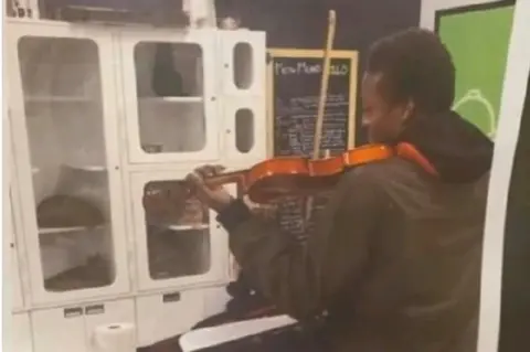 CBS / Mari Newman Mr McClain playing violin to cats in a shelter