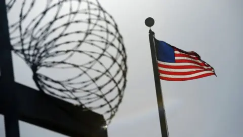 Reuters A US flag flies above a razorwire-topped fence at Guantanamo Bay. File photo