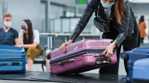 izusek Woman lifting luggage off carousel at airport