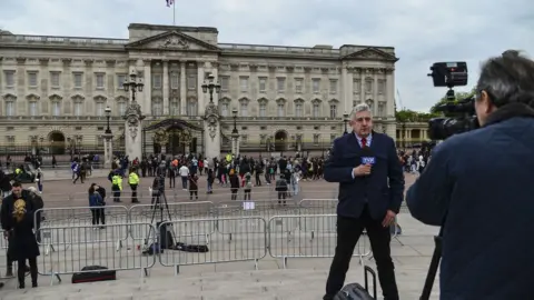 Getty Images A news broadcaster speaks to camera as members of the public queue to read the official notice of the birth of a baby boy to the Duke and Duchess of Sussex outside Buckingham Palace on May 6, 2019