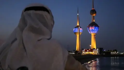 Getty Images A man looking at the projection of New Zealand flag in Kuwait