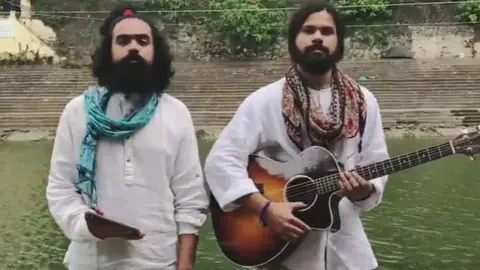 YouTube/VoiceofRam A screengrab from the video shows two bearded male musicians, one holding a guitar