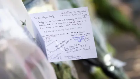 Reuters A sympathy card attached to flowers outside Buckingham Palace on 9 April 2021