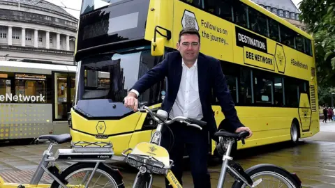 TfGM Andy Burnham poses with bike, bus and tram