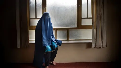 Getty Images Woman covered with a burqa in a home