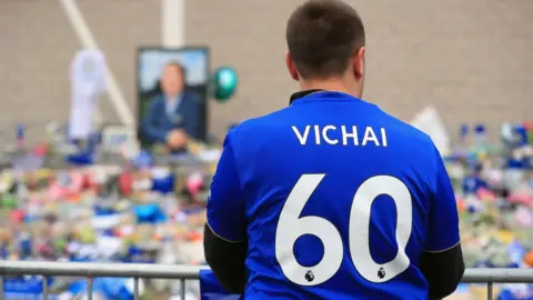 PA Leicester City fan looks over tributes in Vichai shirt