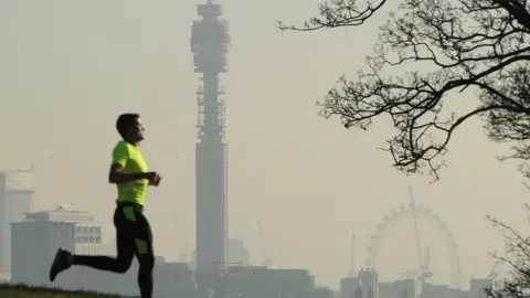 Getty Images A man running against a backdrop of a London skyline showing polluted air